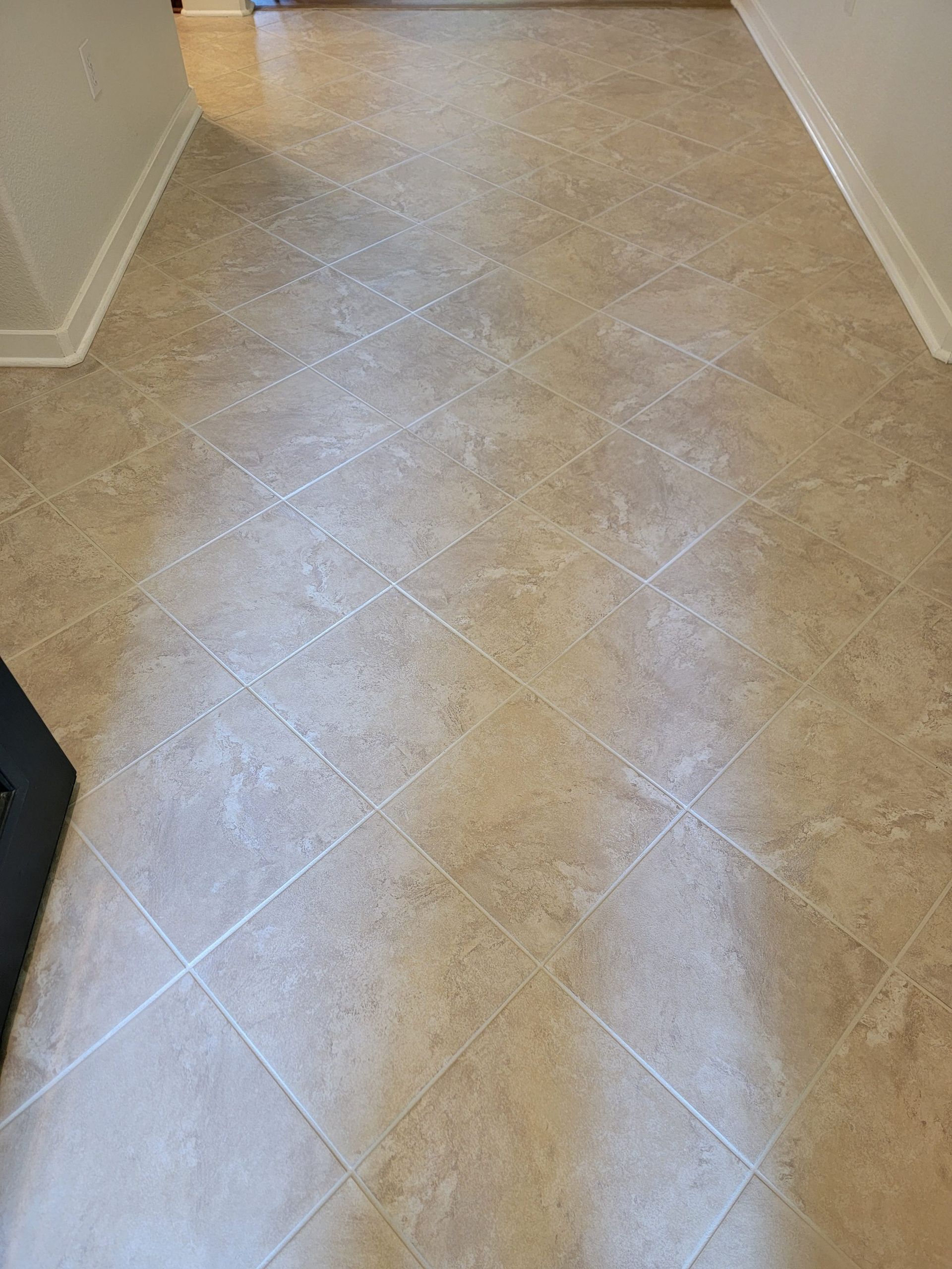 Empty beige carpeted hallway with white walls and baseboards
