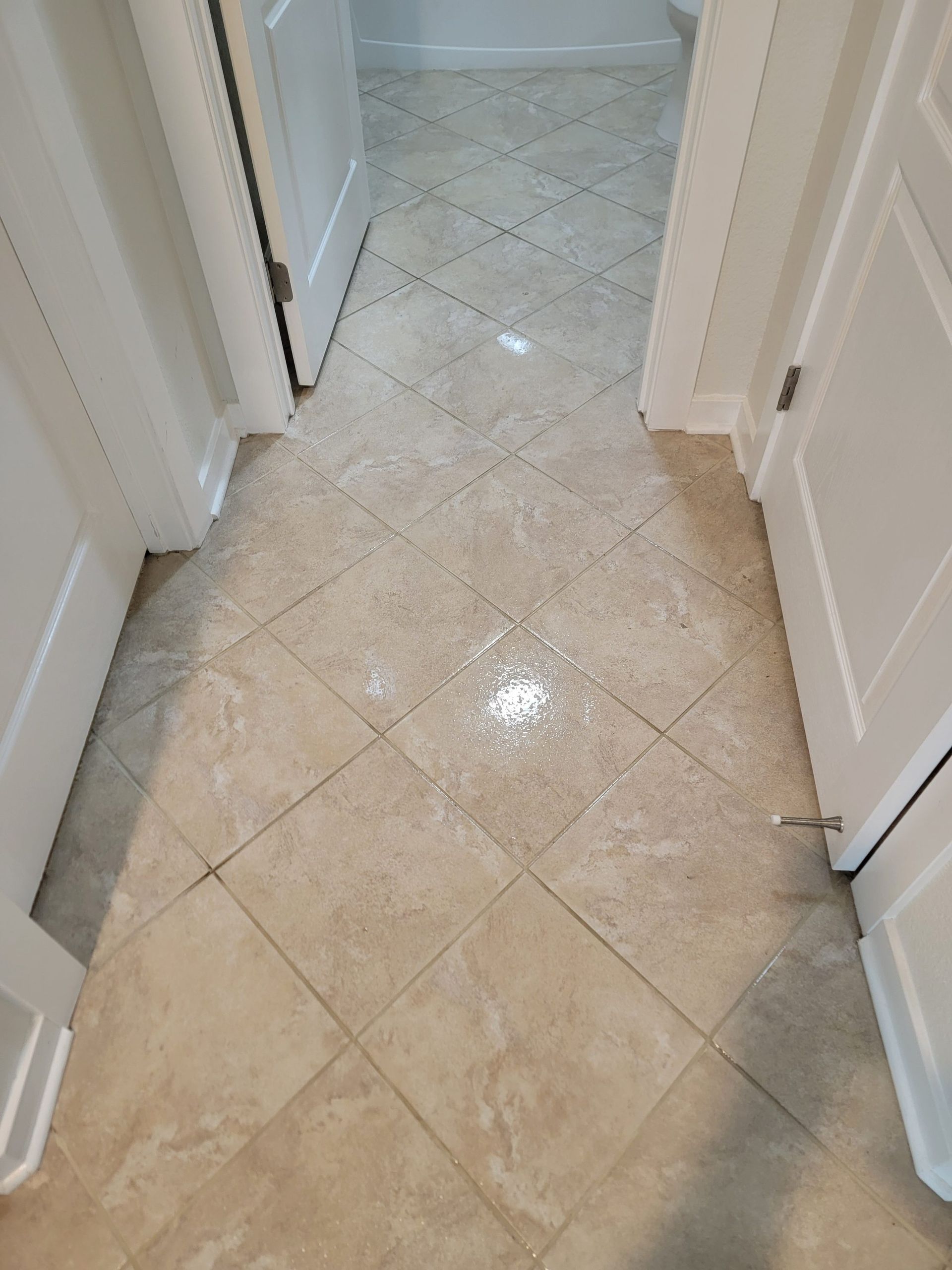 Beige tiled hallway floor with white doorframes and a doorway ahead