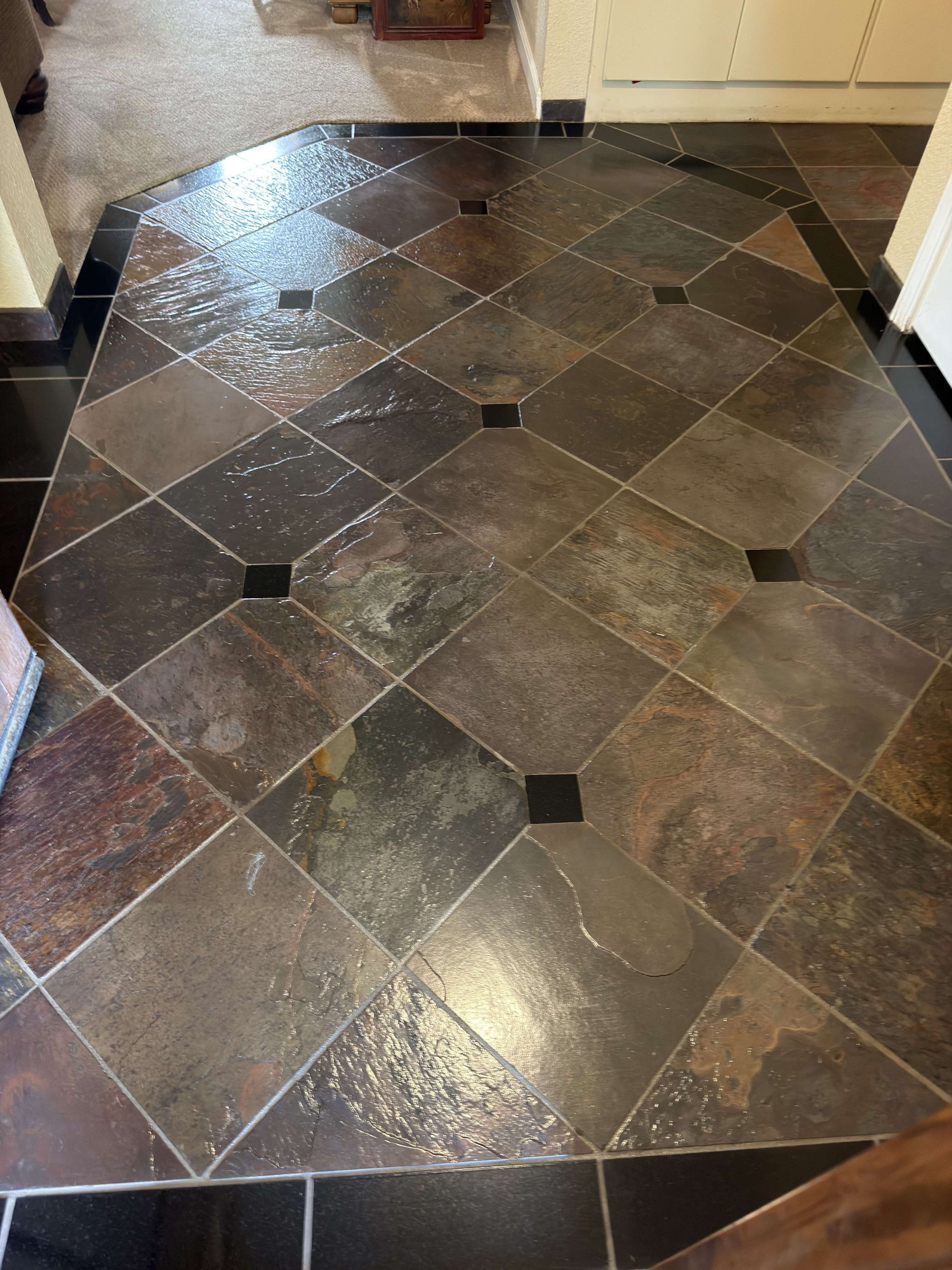 Glossy dark tile floor with diamond pattern and small black accent tiles in a hallway