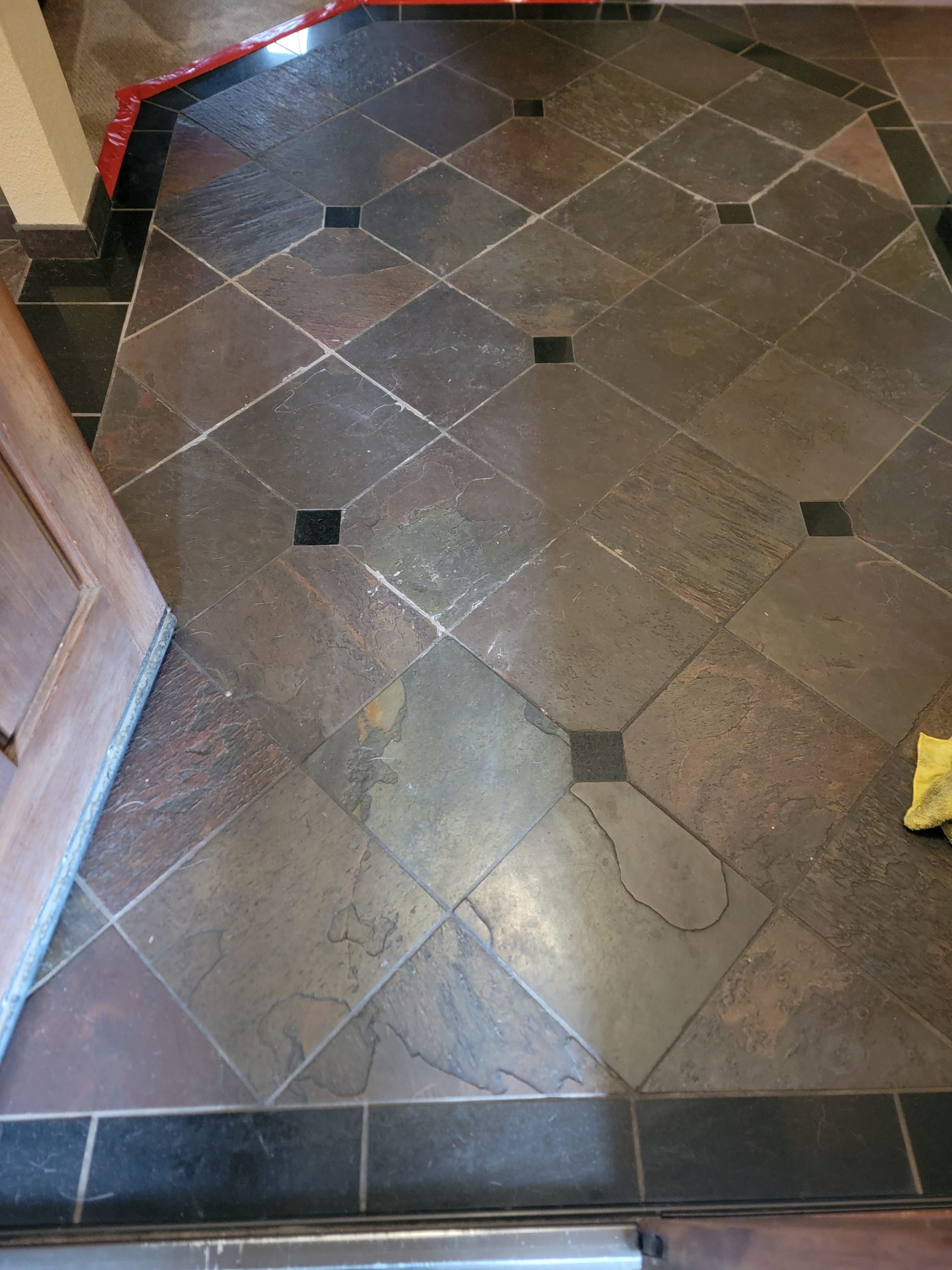 Tiled floor with dark border trim and a few small black square inlays, viewed from above