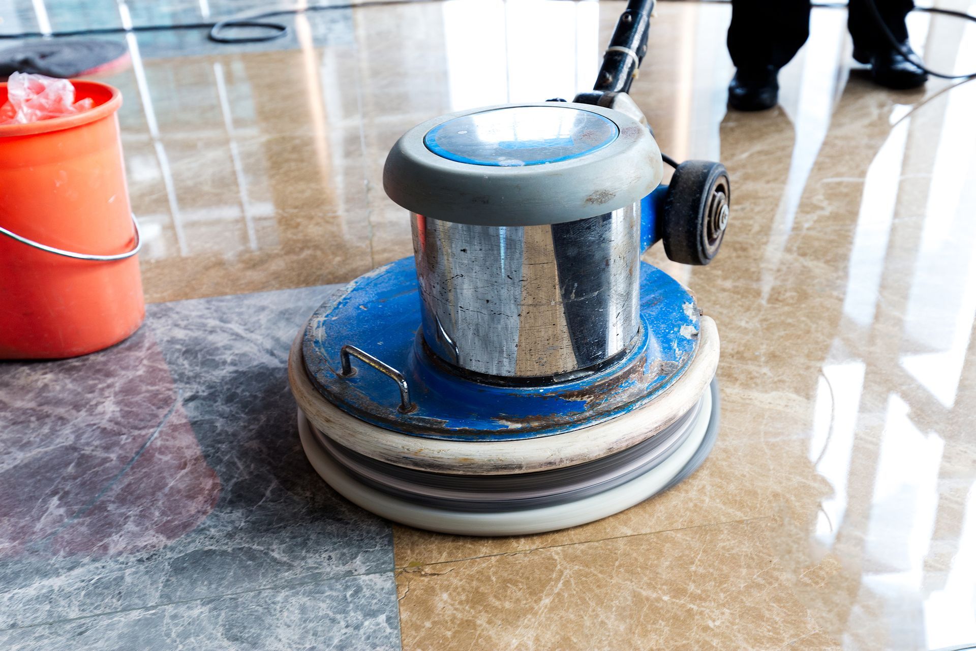 A person is polishing a marble floor with a machine.