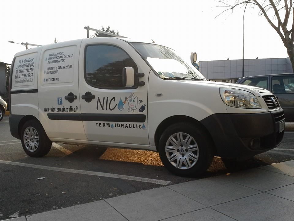 Furgone bianco di servizio parcheggiato all'esterno; il logo recita 