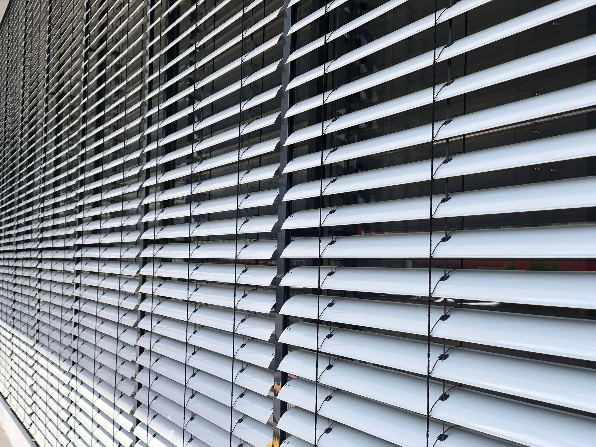 White closed window shutter above a window with a glass screen.
