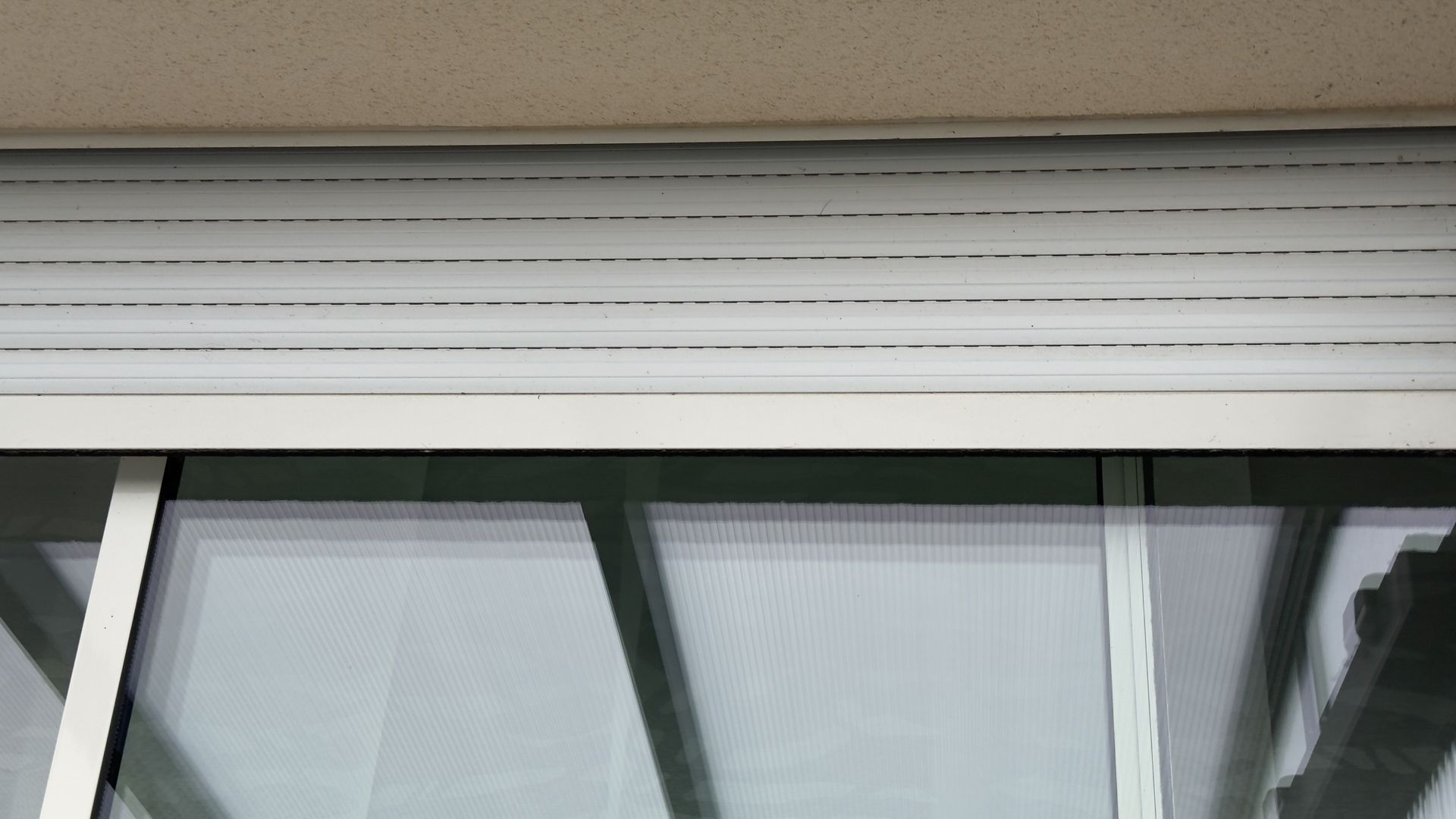 White closed window shutter above a window with a glass screen.