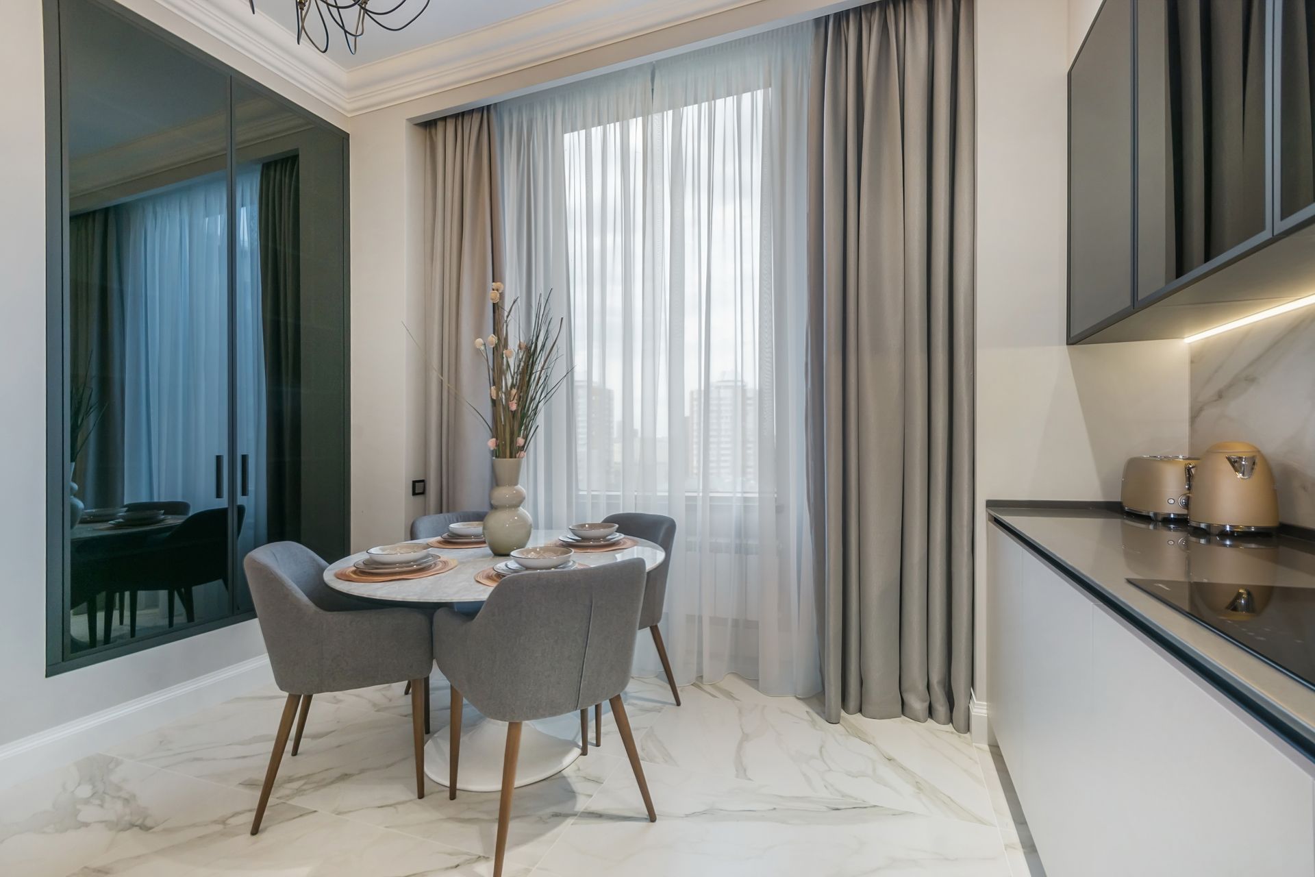 White sheer curtains hanging in front of a window, with wavy lower edge over a wooden floor.