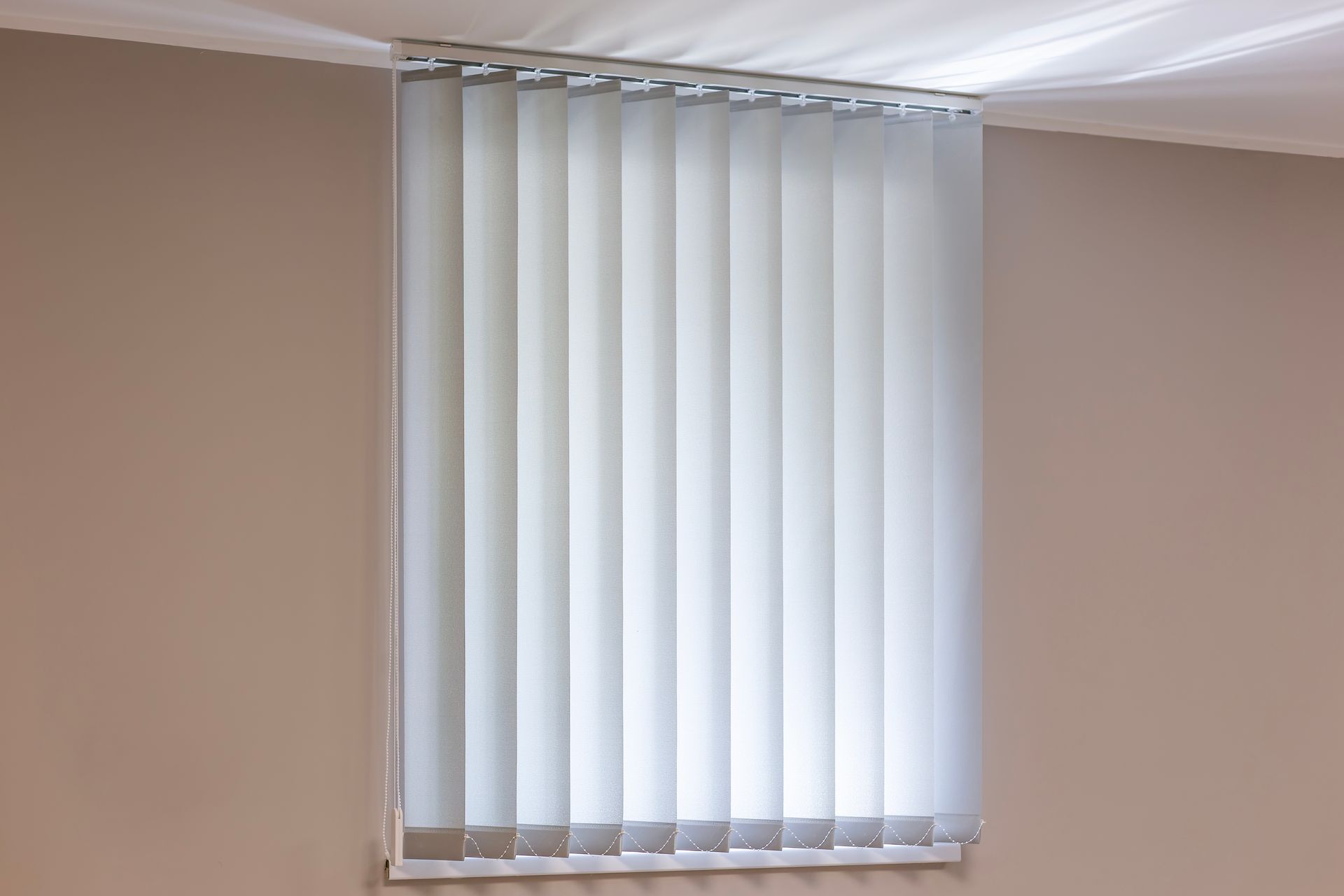 White sheer curtains hanging in front of a window, with wavy lower edge over a wooden floor.