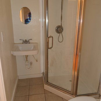 A bathroom with a sink , toilet , shower and mirror.