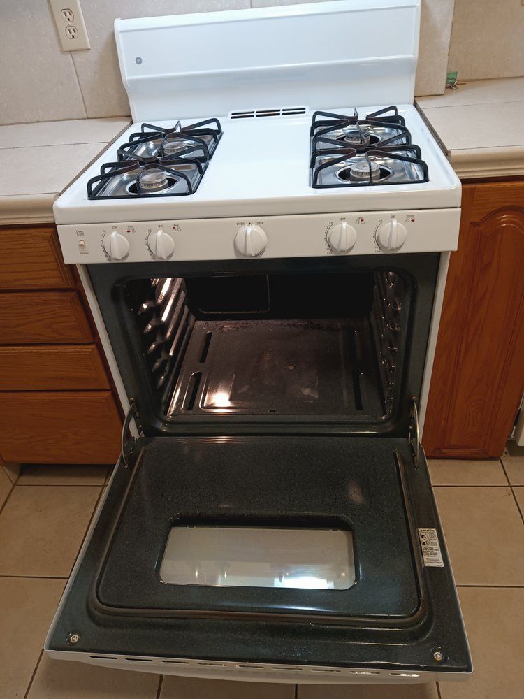 A white gas stove with the door open in a kitchen