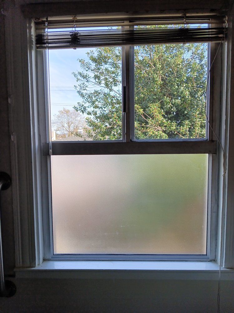 A window with a blind on it and a view of trees.