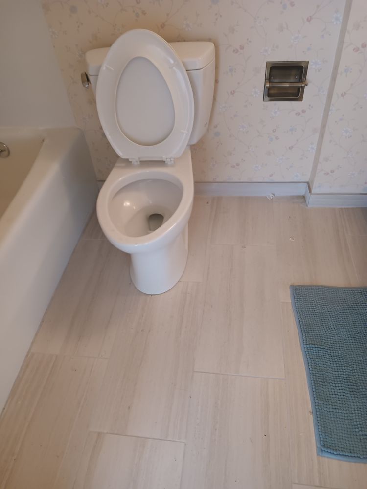 A white toilet is sitting in a bathroom next to a bathtub.