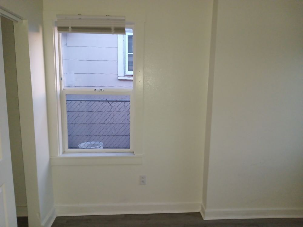 An empty room with a window and a fence in the background.