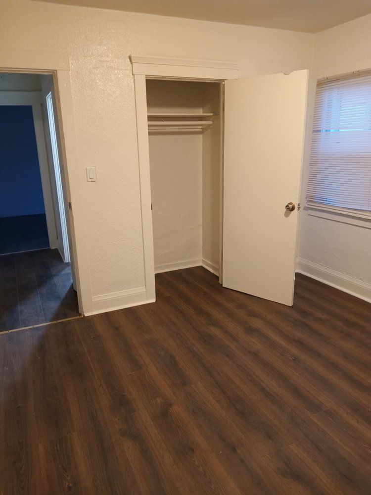 An empty room with a closet and a window.