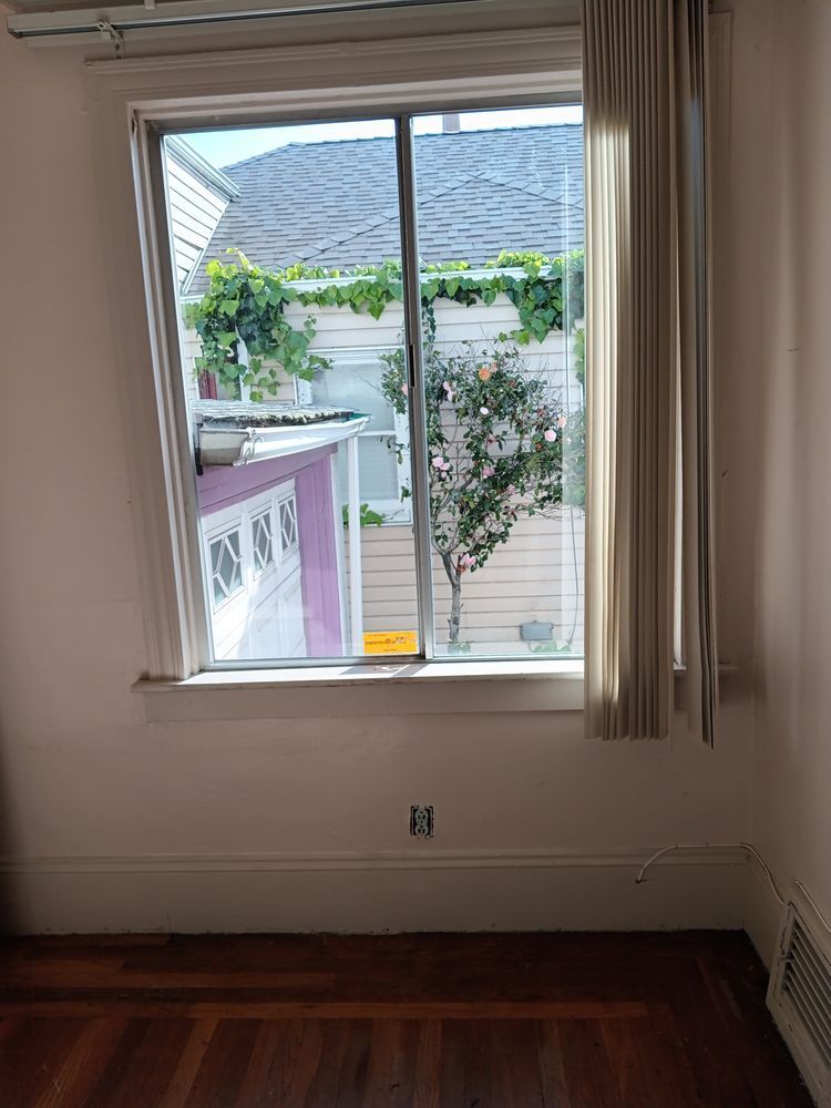 An empty room with a large window and curtains.