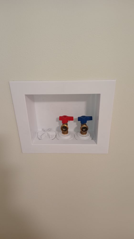 A washer and dryer outlet in a recessed niche on a wall.