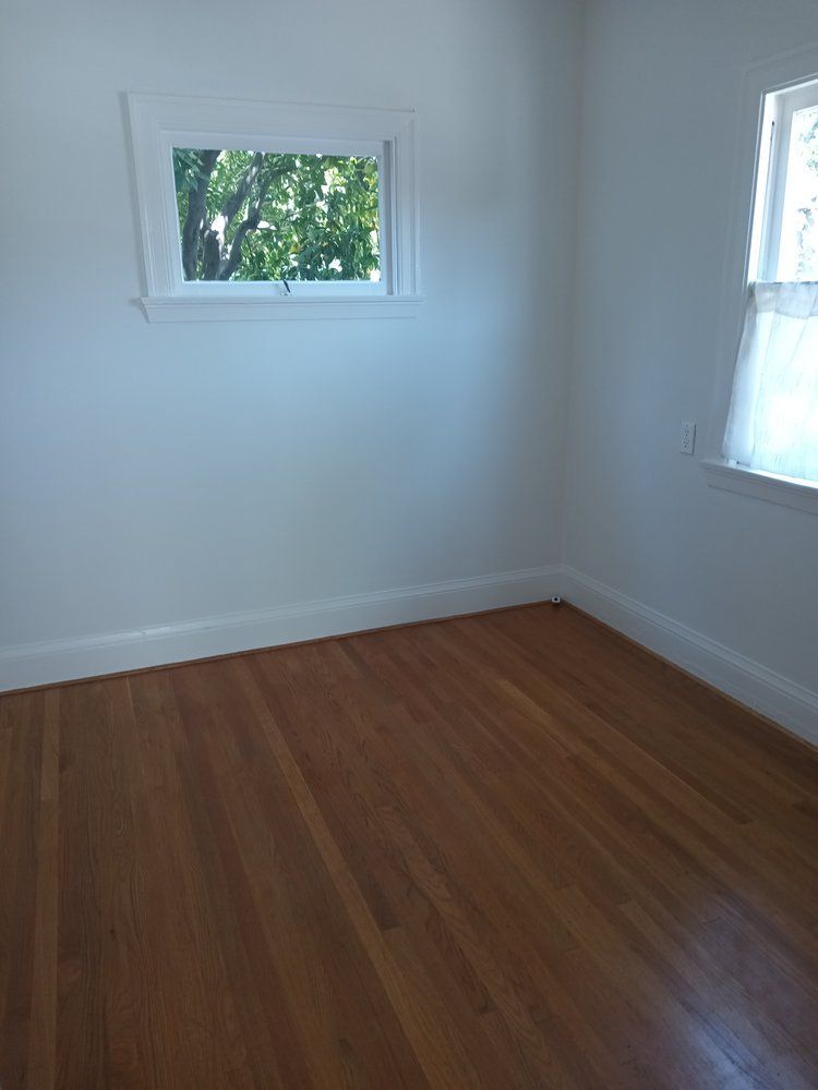 An empty room with hardwood floors and a window