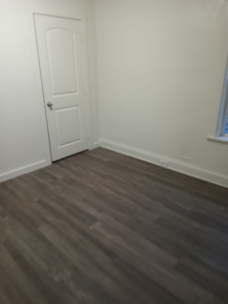An empty room with a wooden floor and a white door.