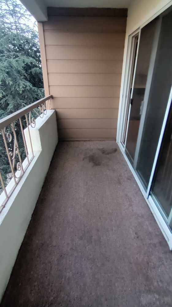 An empty balcony with a sliding glass door and a railing.