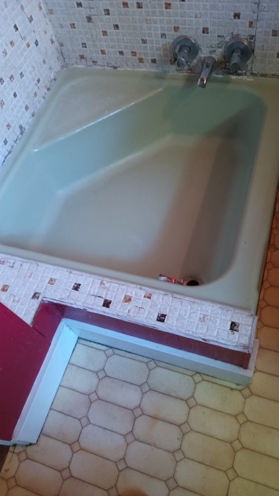 A bathtub is sitting in a bathroom next to a tiled wall.