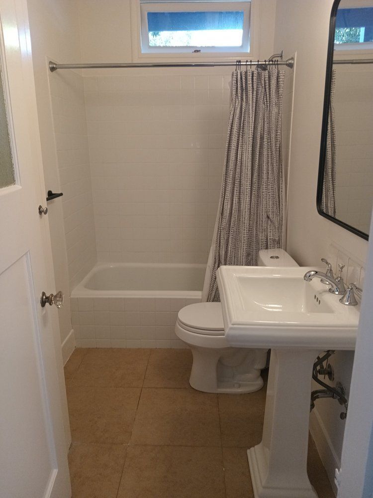 A bathroom with a sink , toilet , tub and mirror.