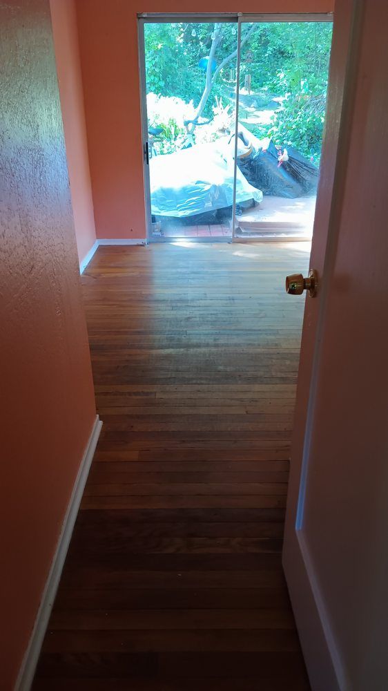 A hallway with hardwood floors and a sliding glass door leading to a patio.