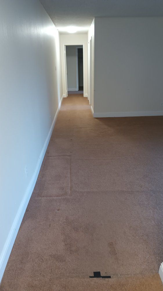 A long hallway with a brown carpet and white walls.
