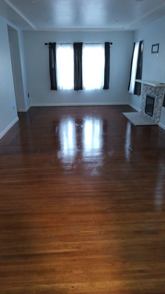 An empty living room with hardwood floors and a fireplace.