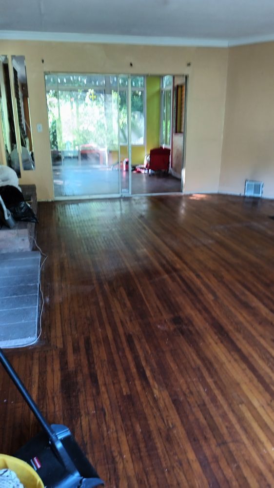 An empty living room with hardwood floors and a vacuum cleaner.