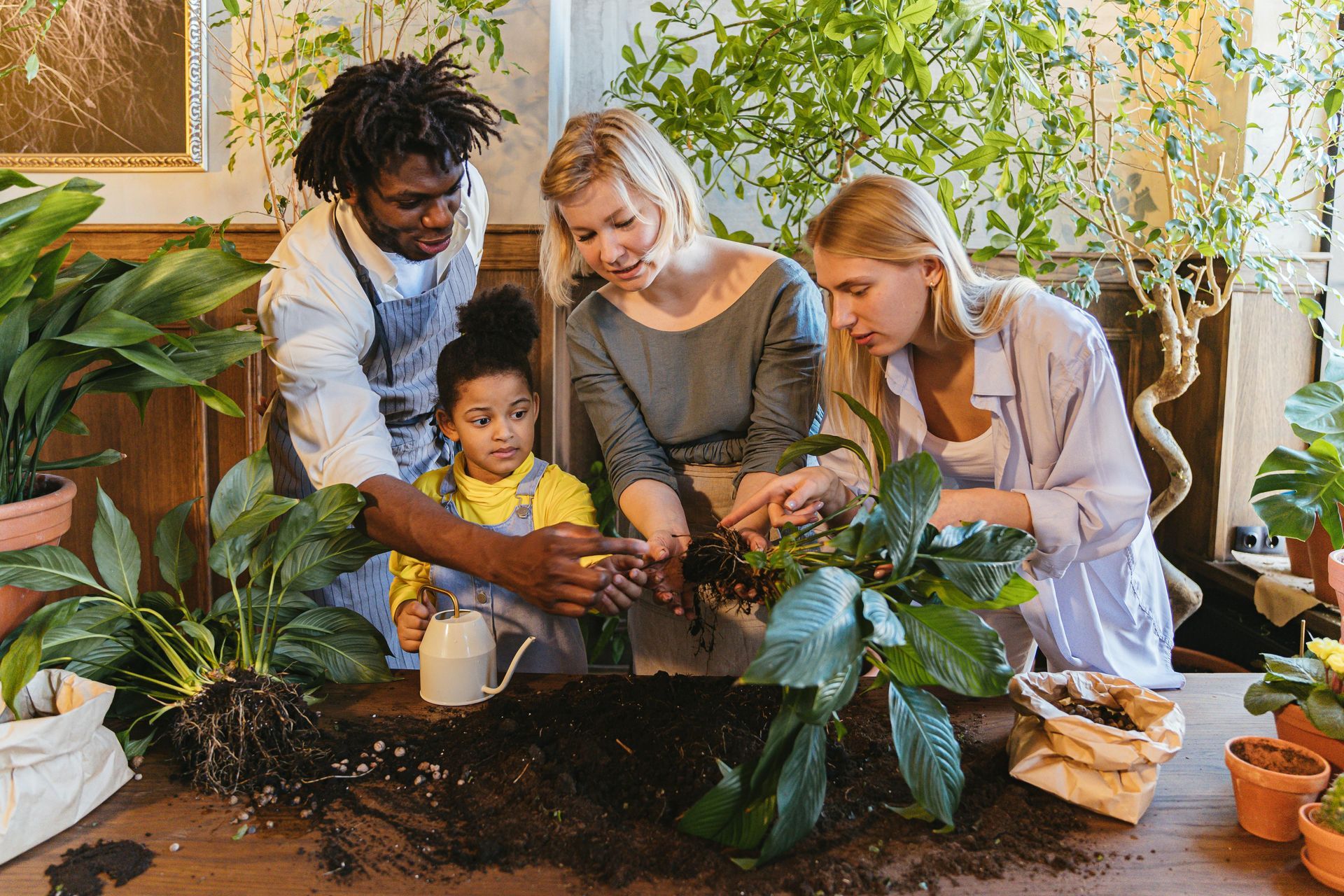 A group of people are sitting around a table planting plants.