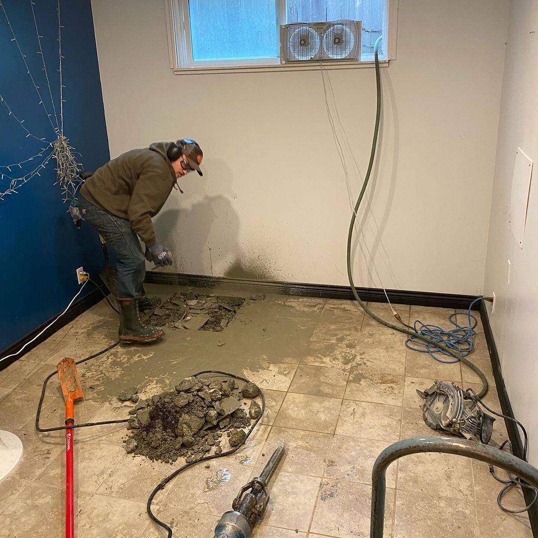 A man is digging a hole in the floor of a room.