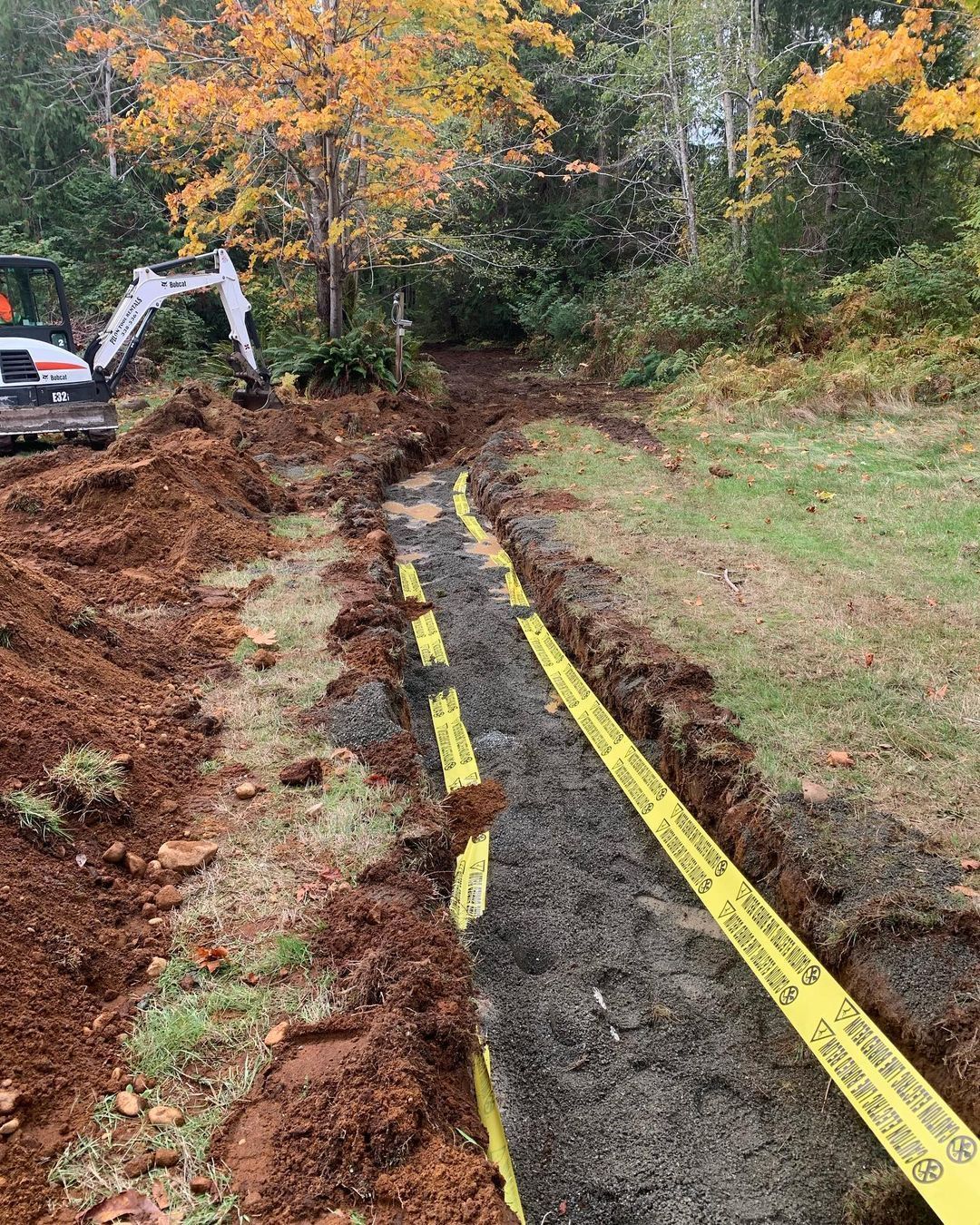 A bulldozer is digging a trench in a yard.