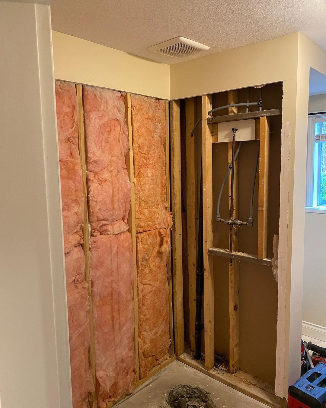 A bathroom with a shower being installed in the wall.