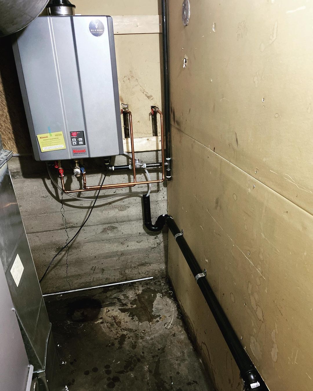 A water heater is sitting in a corner of a room next to a wall.