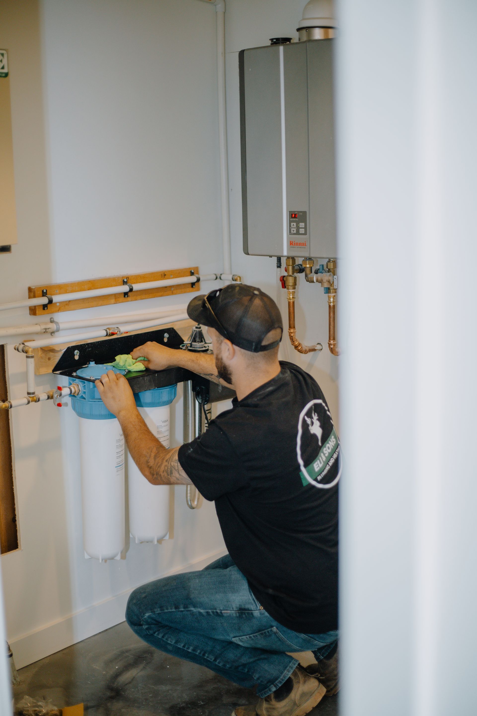 A man is working on a water filter in a bathroom.