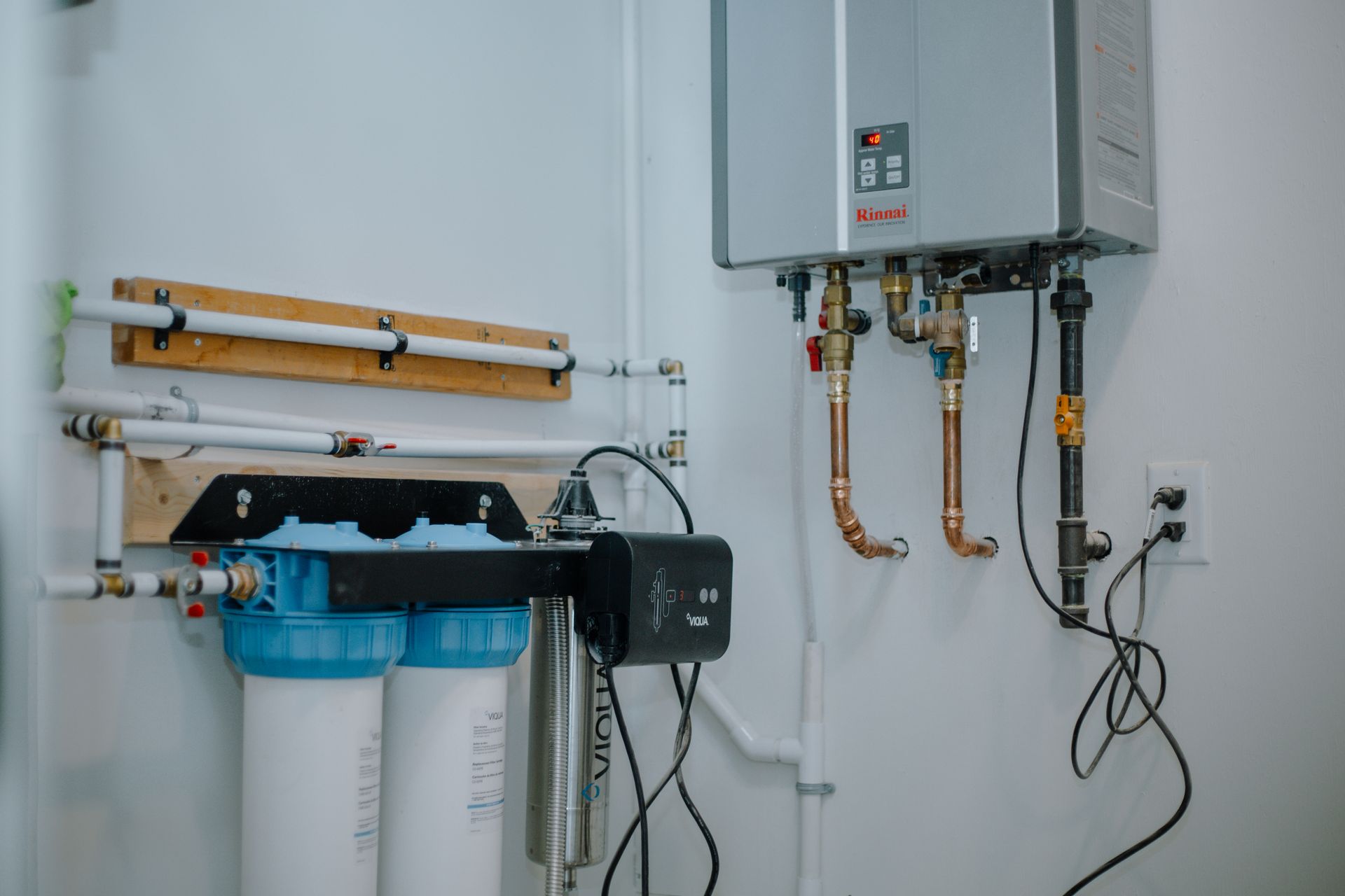 A room with a water heater and a water filter hanging on the wall.