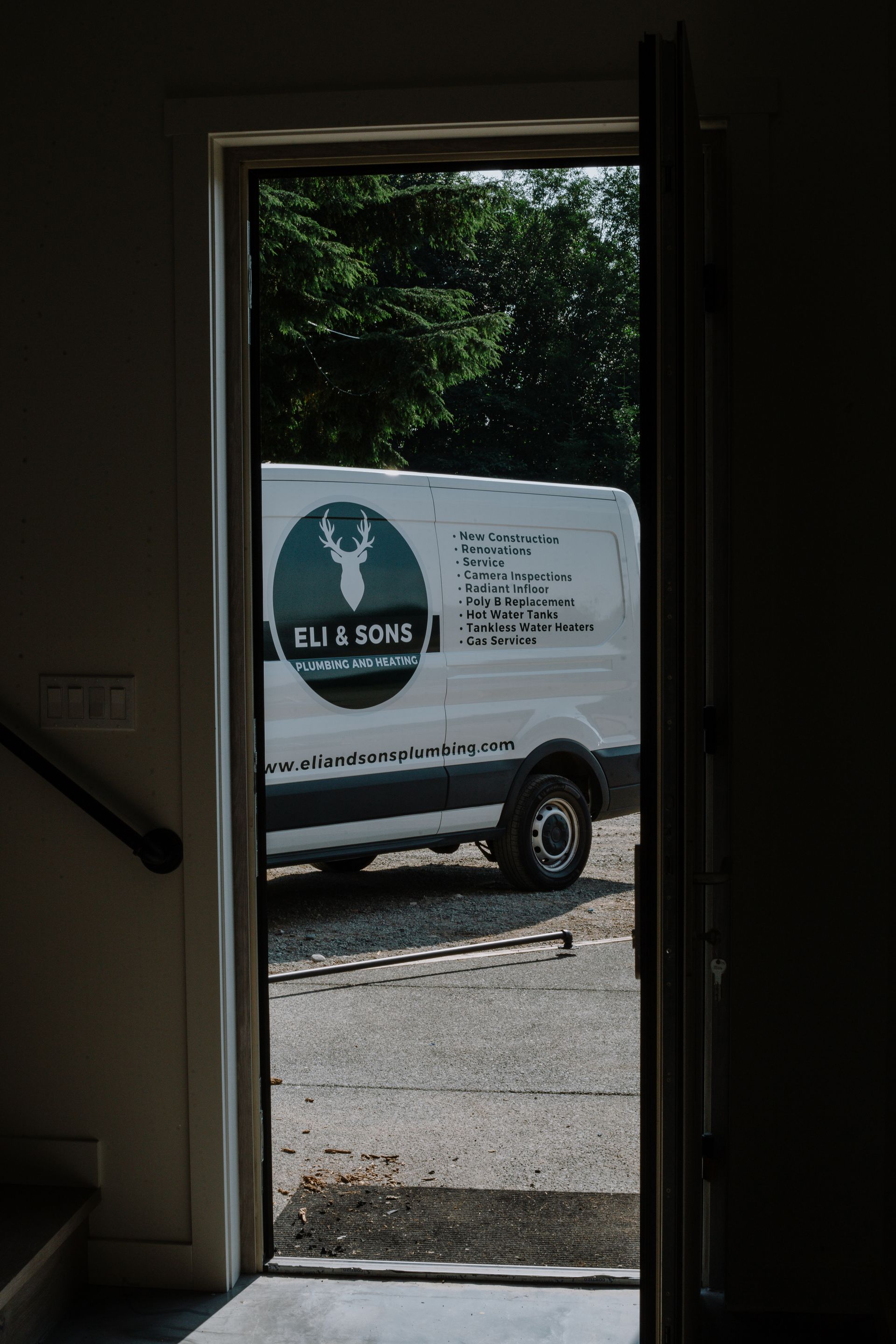 A white van is parked in front of a door.