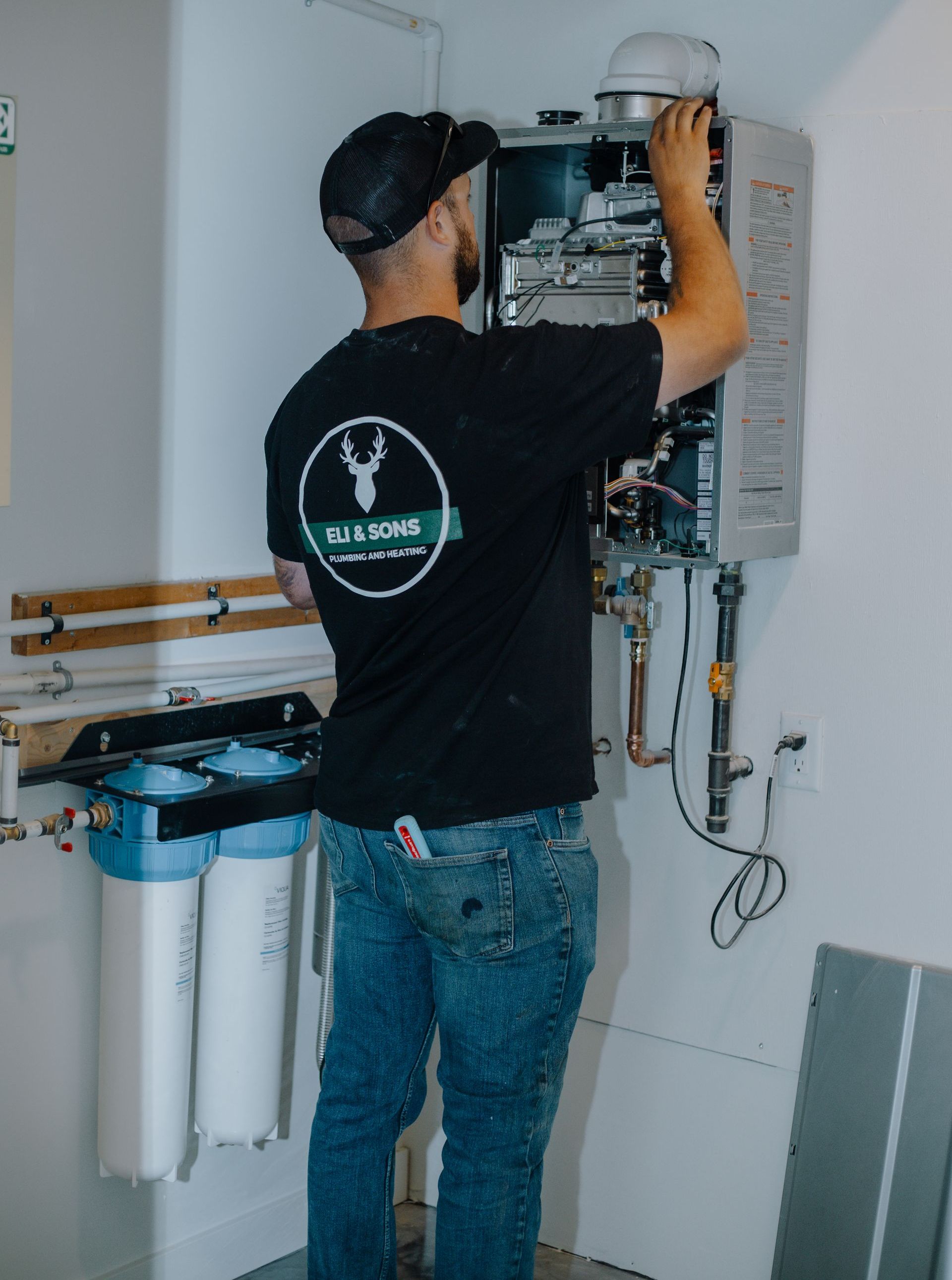 A man is working on a water heater in a bathroom.