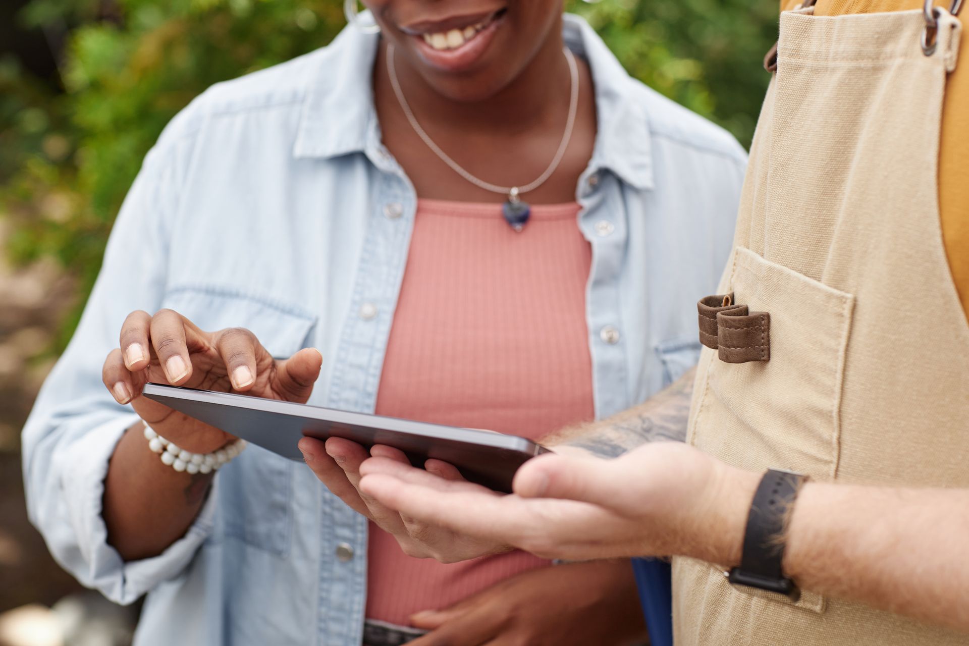 A close-up of a client touching the digital tablet screen of a landscape designer next to her.