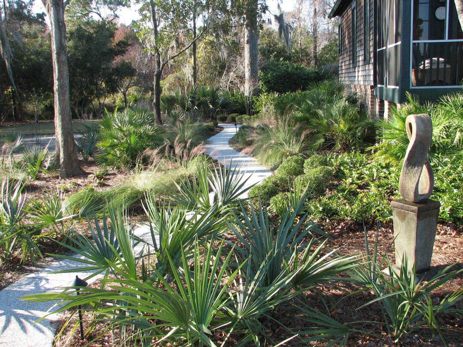 A path leading to a house surrounded by trees and plants