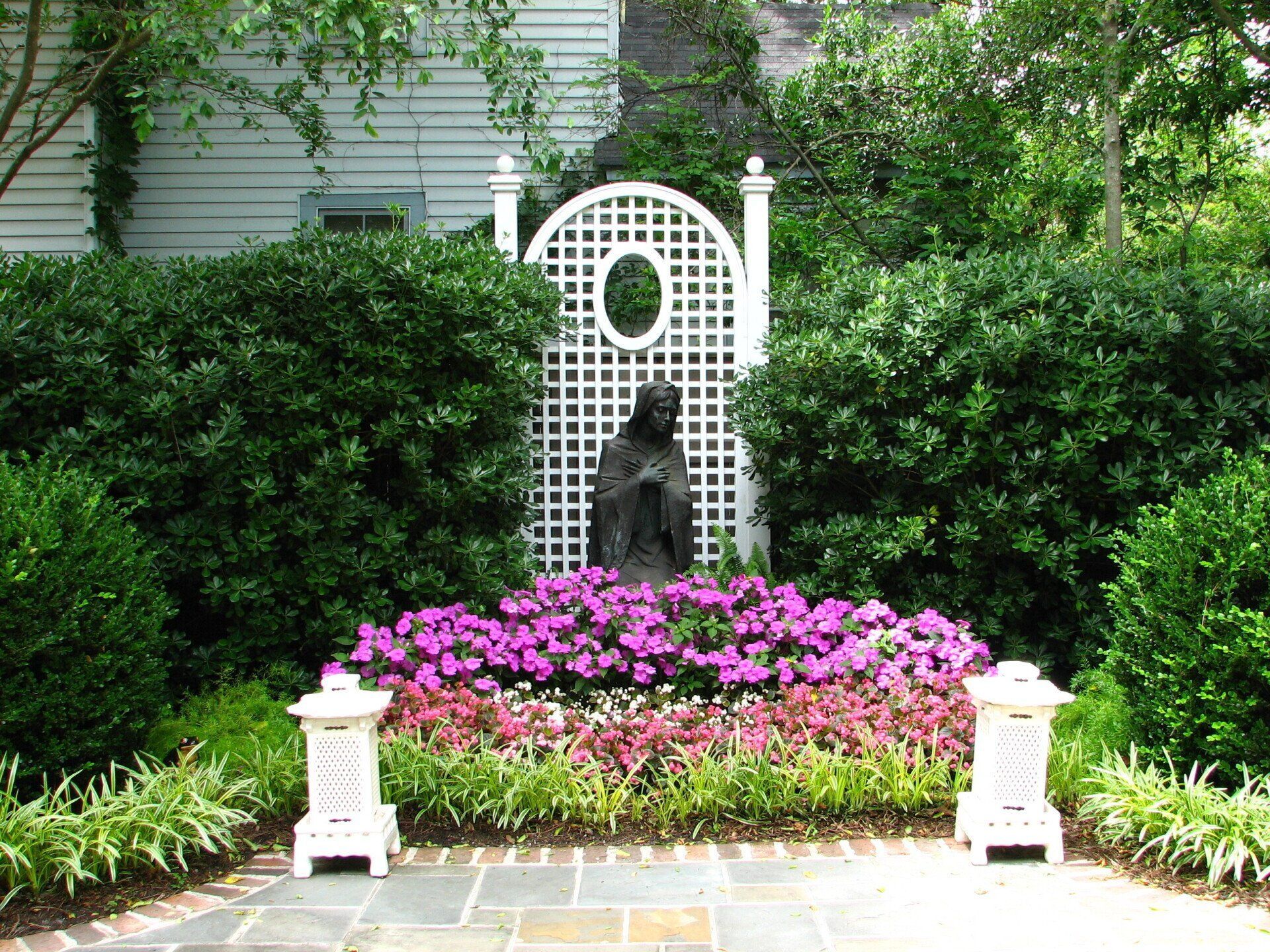 A garden with purple flowers and a statue in the middle