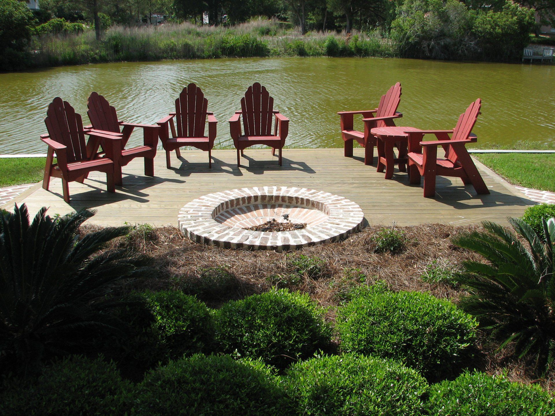 A fire pit sits in the middle of a patio surrounded by chairs