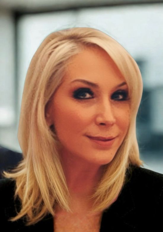 Person working at a desk with a laptop, a plant, and a vase with eucalyptus. Wooden stool nearby.