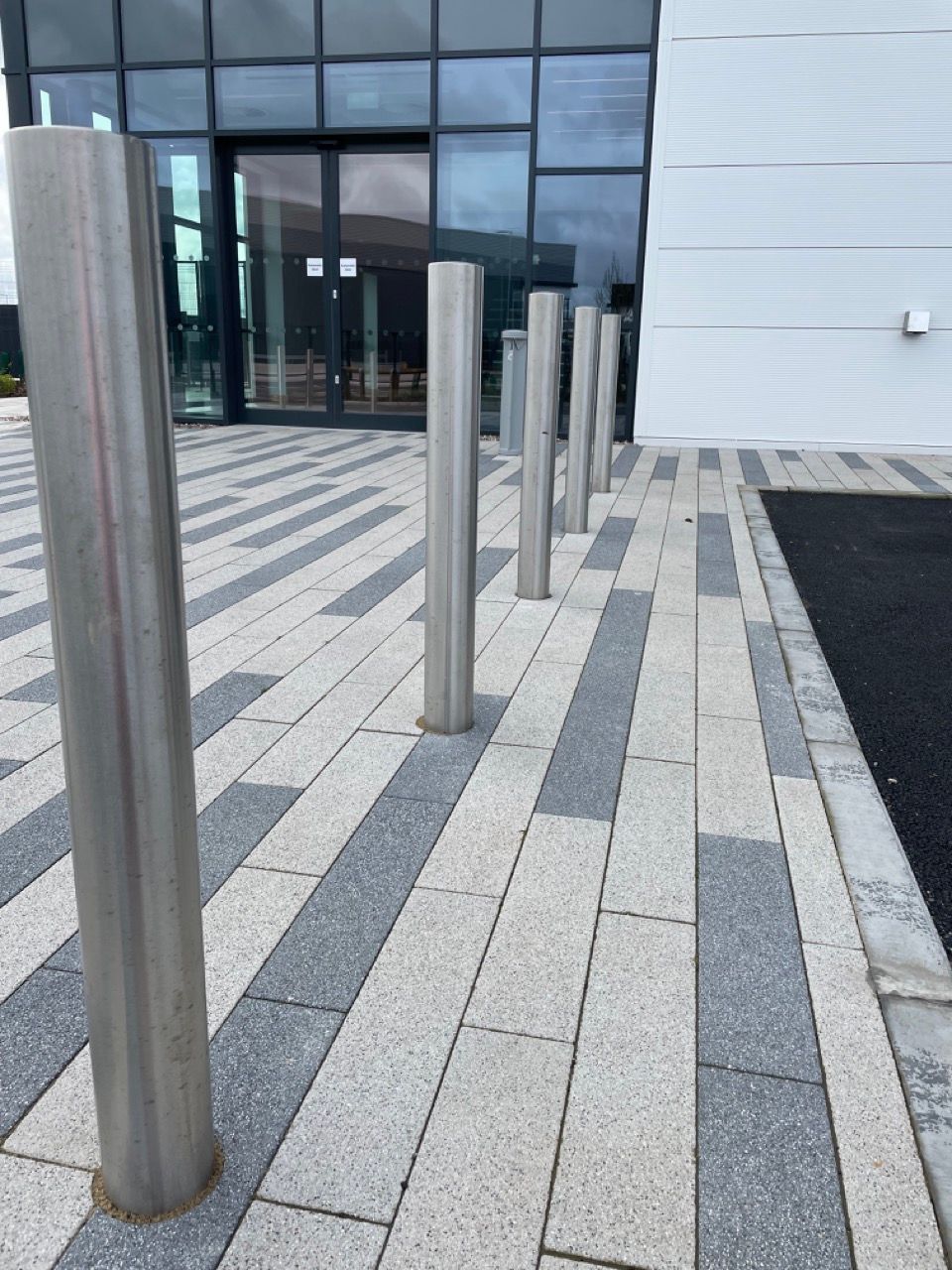 A row of stainless steel poles are lined up in front of a building.