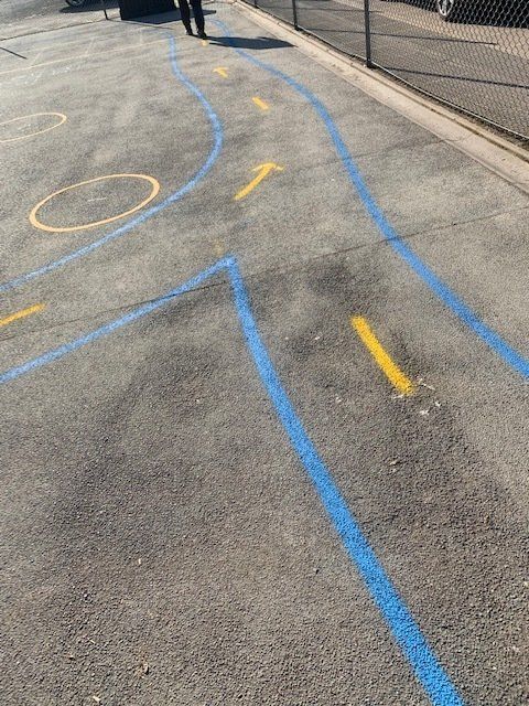 A person is walking down a street with blue and yellow lines painted on it.