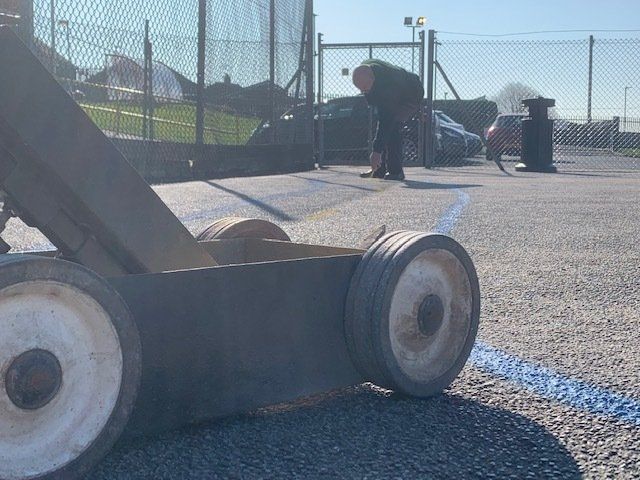 A man is using a machine to paint a blue line on the ground.