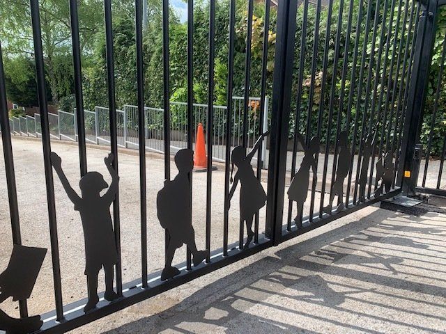 A black gate with silhouettes of children on it.
