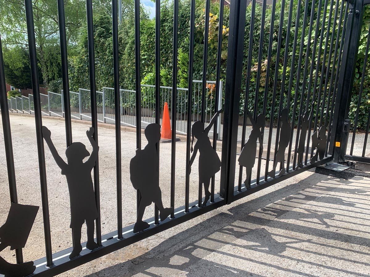 A black gate with silhouettes of children on it.