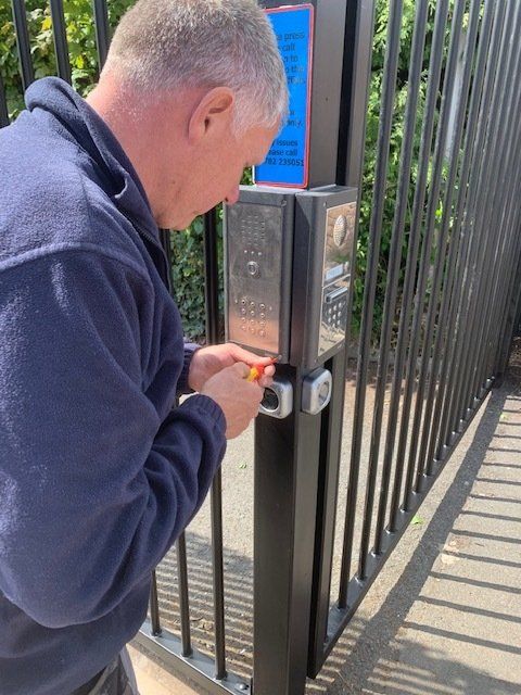 A man is working on a gate with a screwdriver.