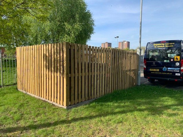 A black van is parked next to a wooden fence.