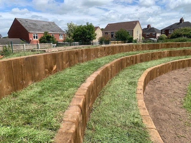 A wooden amphitheater with a lot of grass and houses in the background.