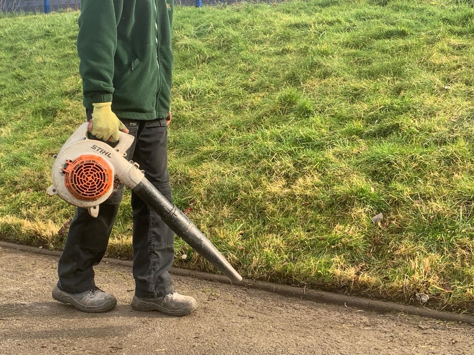 A person is using a leaf blower to clean the grass.